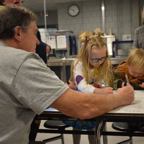 Children and adults working on a large poster