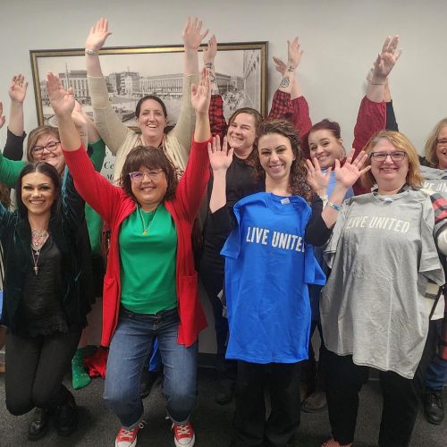 happy people with their hands up wearing live united shirts