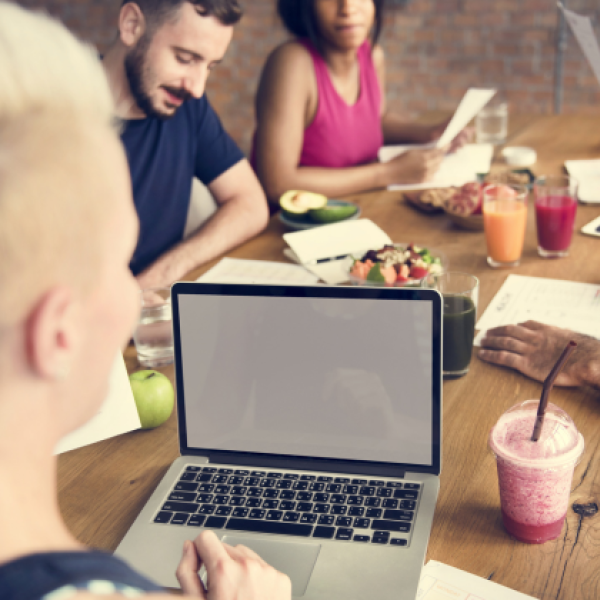 group of young people having a meal and working on their computers