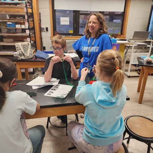 woman working in a classroom with children on a project