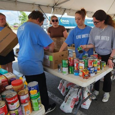 people working together to pack boxes with canned food