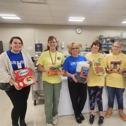 people holding various food products inside of a commercial kitchen