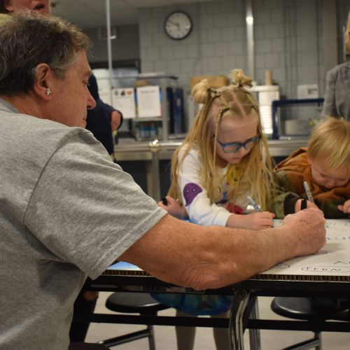 Children and adults working on a large poster