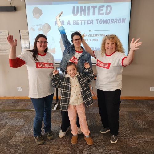 Small group of people wearing LIVE UNITED shirts, raising their arms in joy