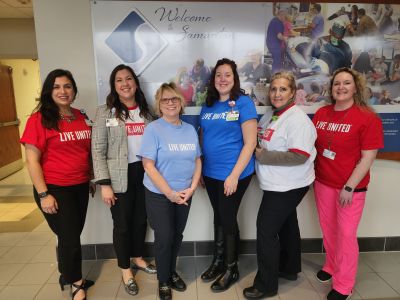 Group of smiling people wearing colorful LIVE UNITED t-shirts