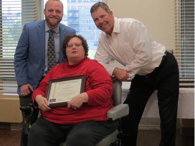 woman accepts framed diploma from city officials