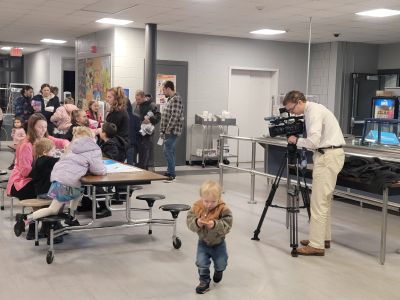 7 News reporter sets up camera at event with child in the foreground
