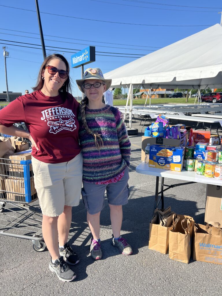 Two volunteers pose near a table at the food drive.
