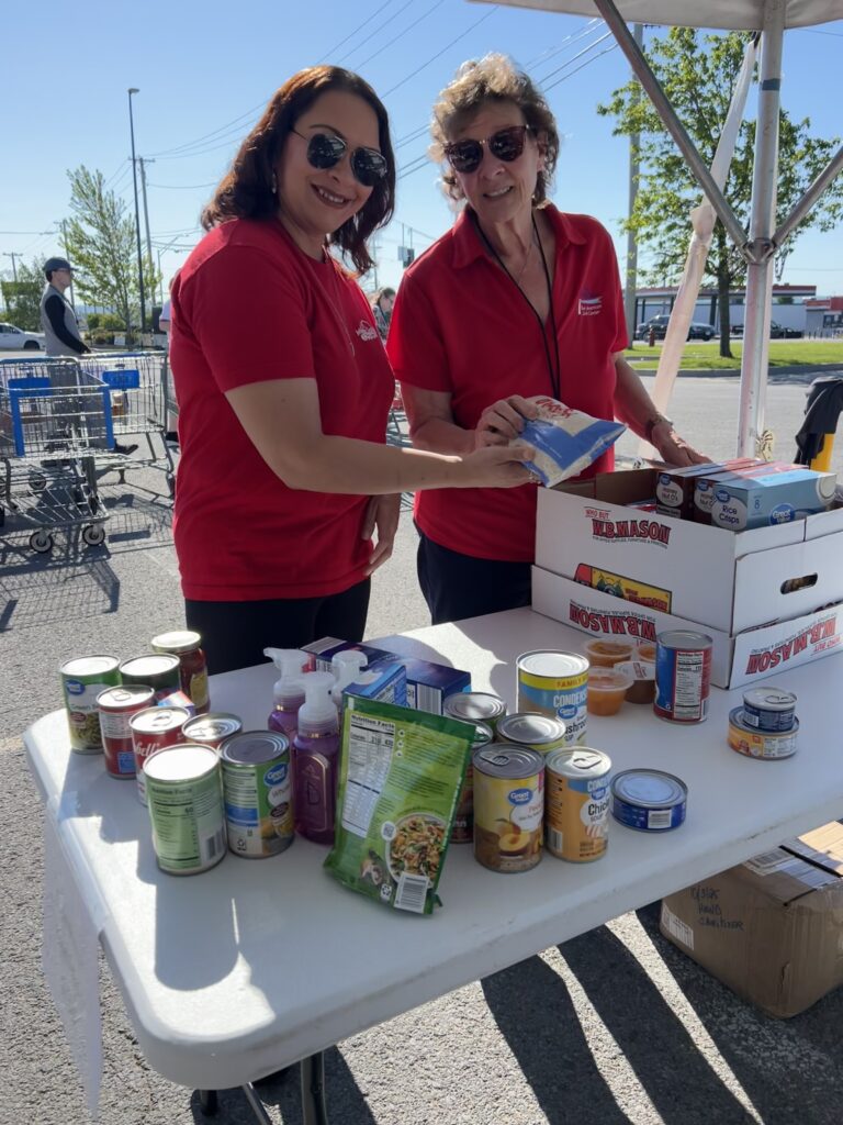Two volunteers take a break from sorting food for a photo.