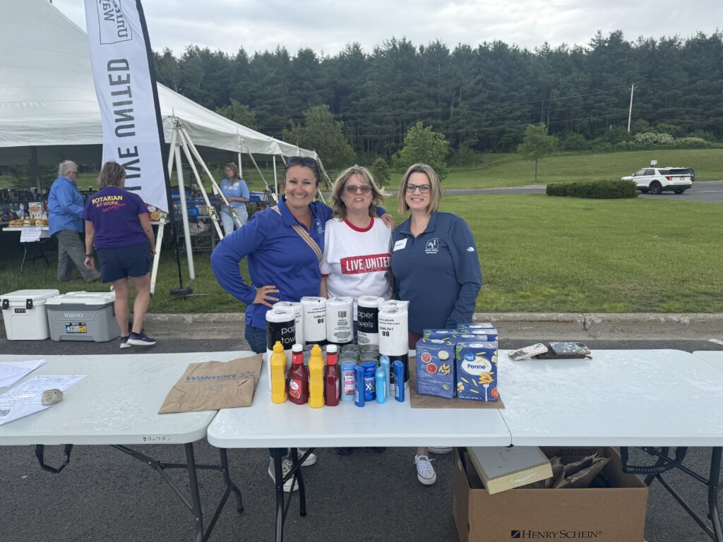 Volunteers pose at food table with donations in foreground.