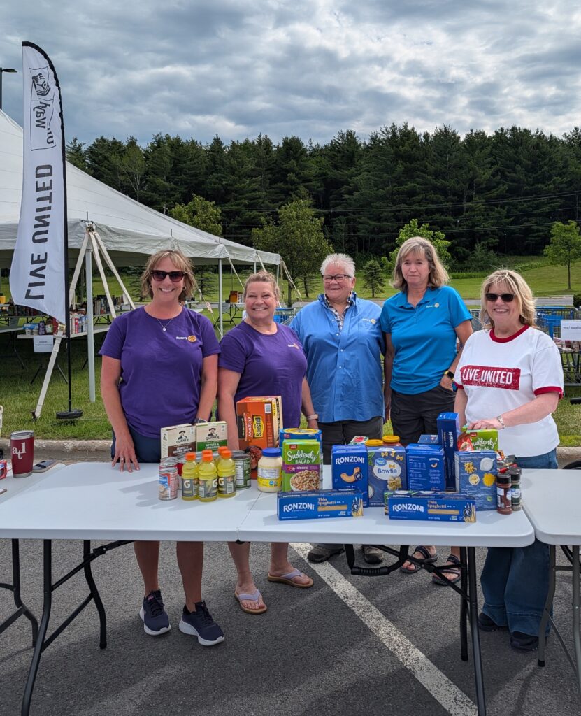 Group of volunteers from Clayton Rotary Club stand behind donation table.
