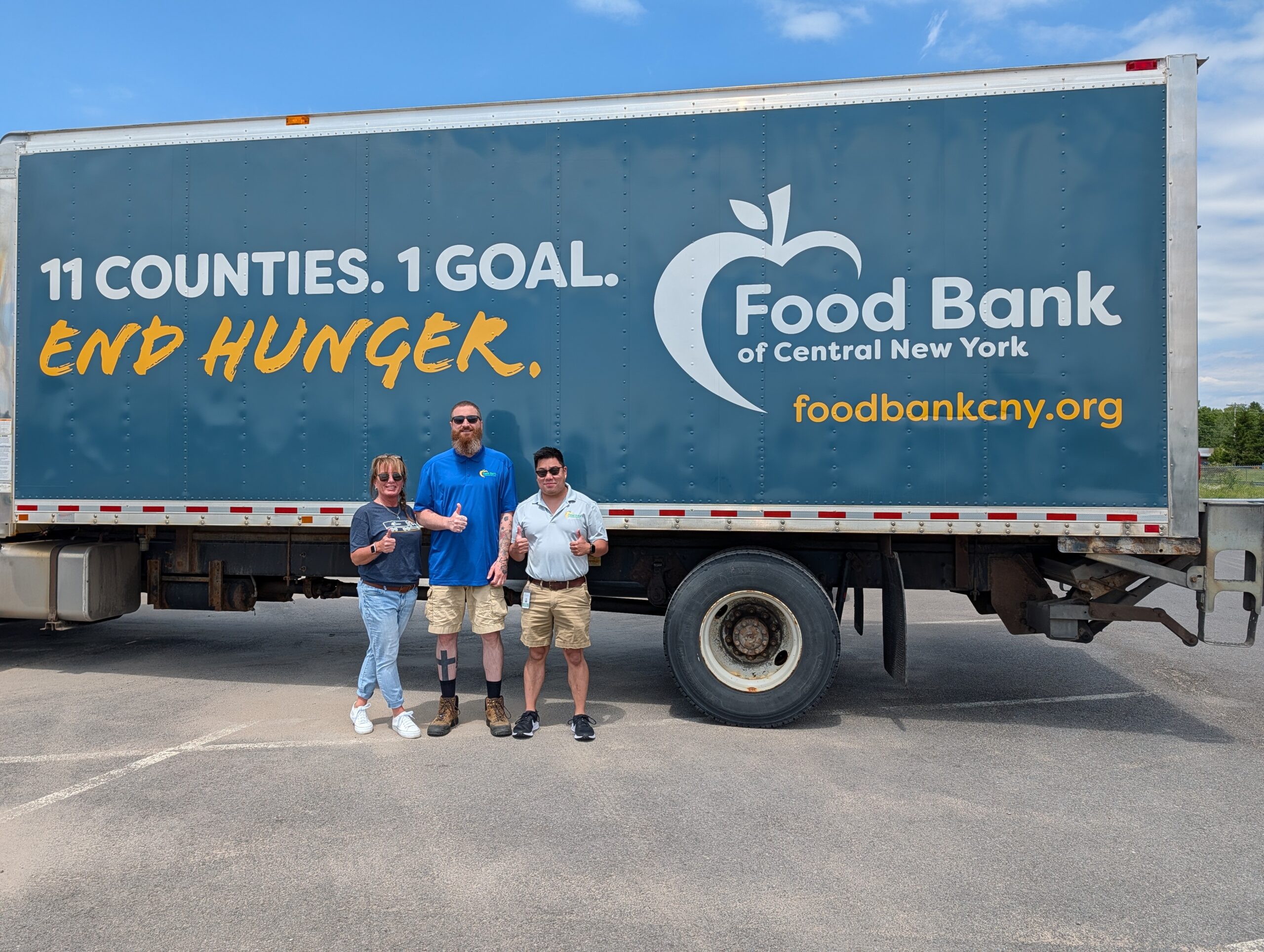 Food Bank of CNY staffers pose in front of the parked truck