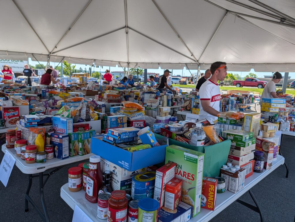Volunteers inside tent placing food on already full tables.
