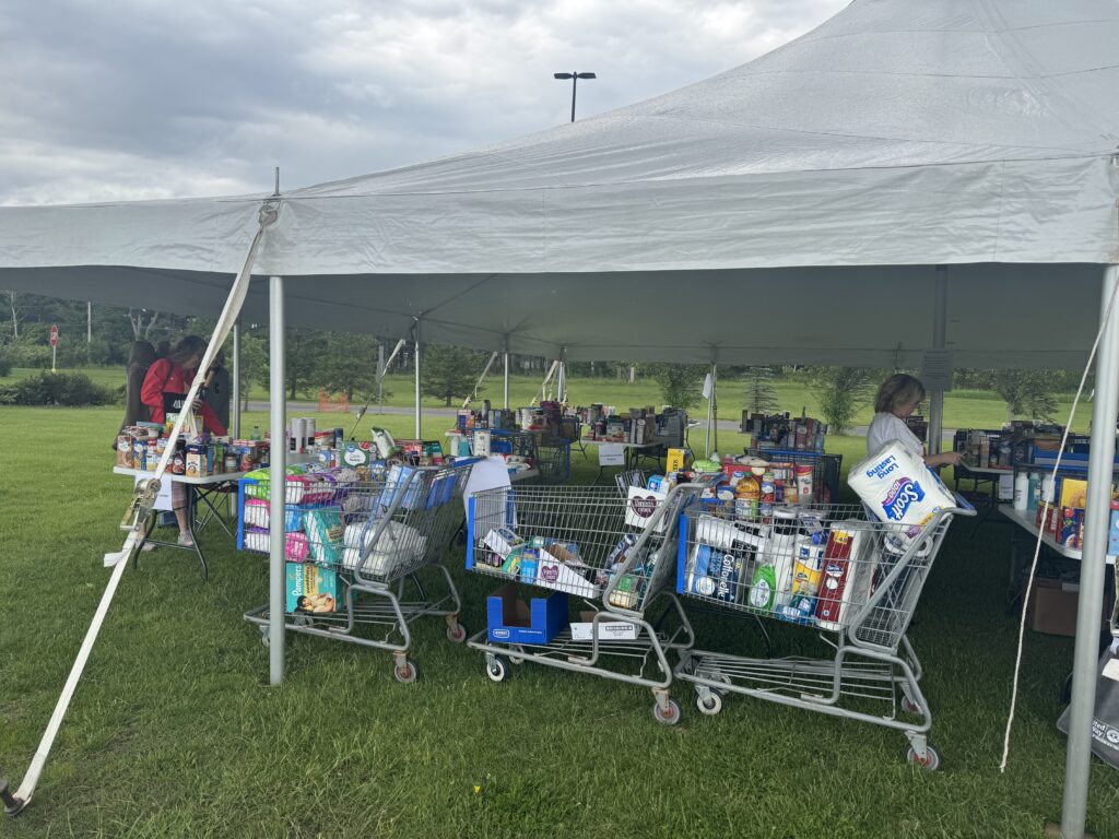 Volunteers working inside tent with carts full of food in the foreground.