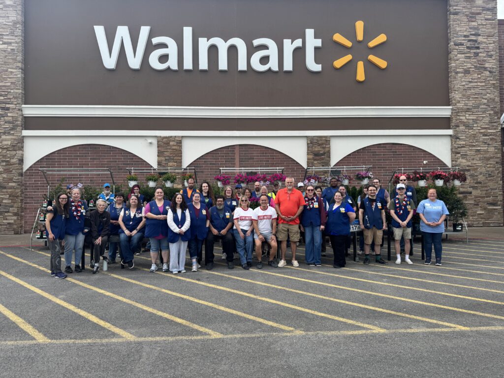 Potsdam Walmart team pose outside store underneath Walmart sign.