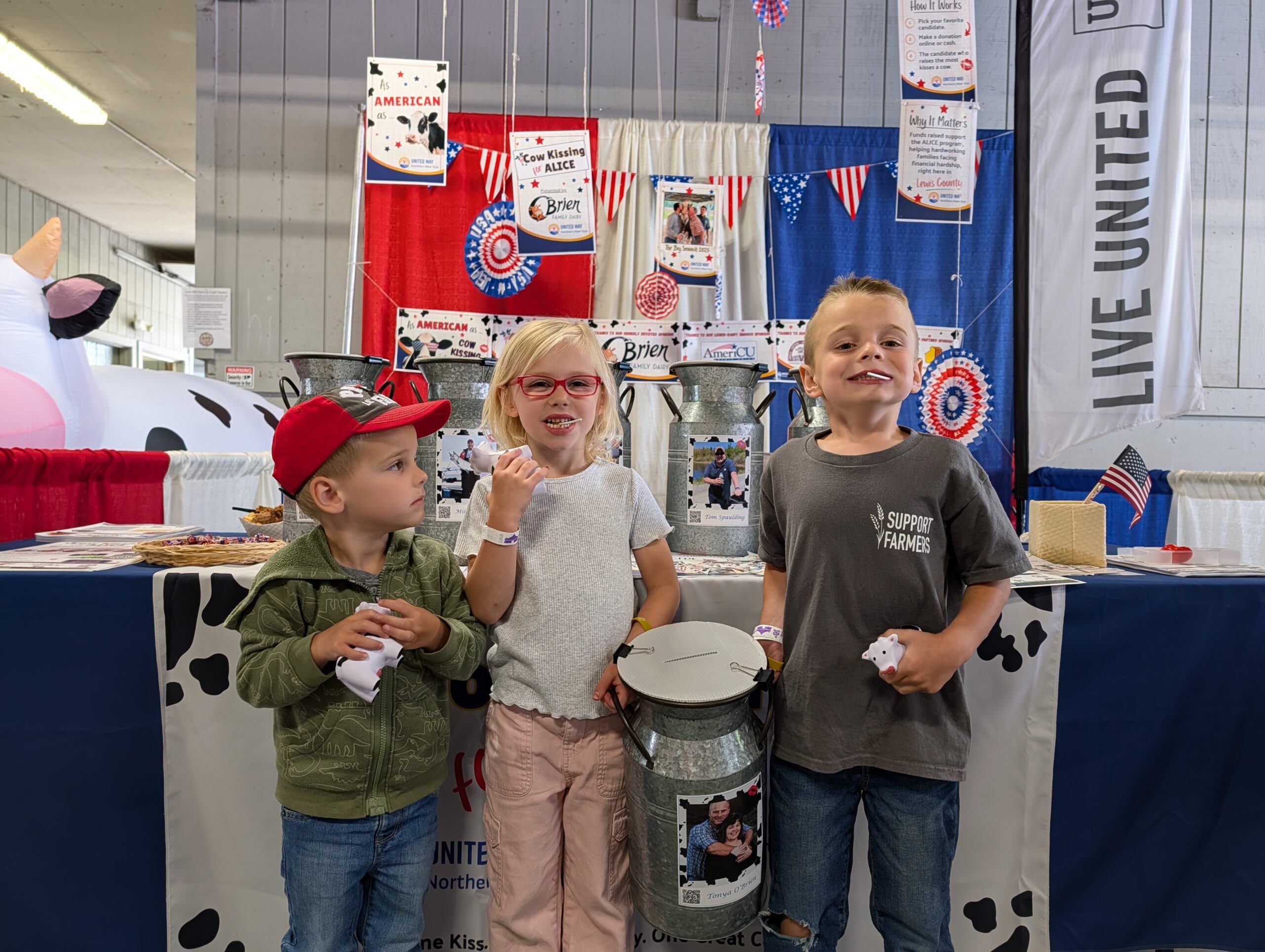 Three kids smiling holding a milk can
