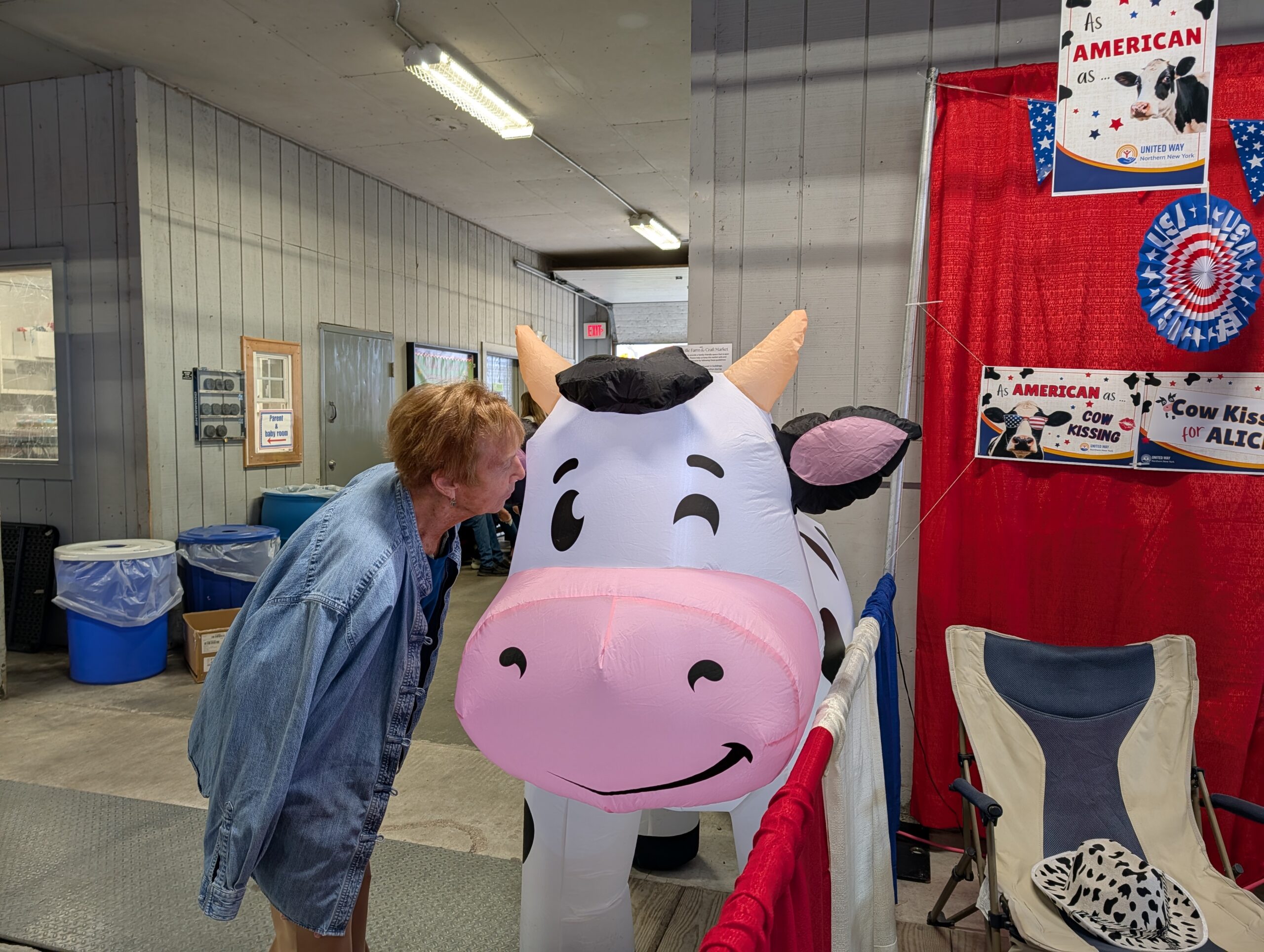 Woman kisses a blow-up cow at the United Way booth
