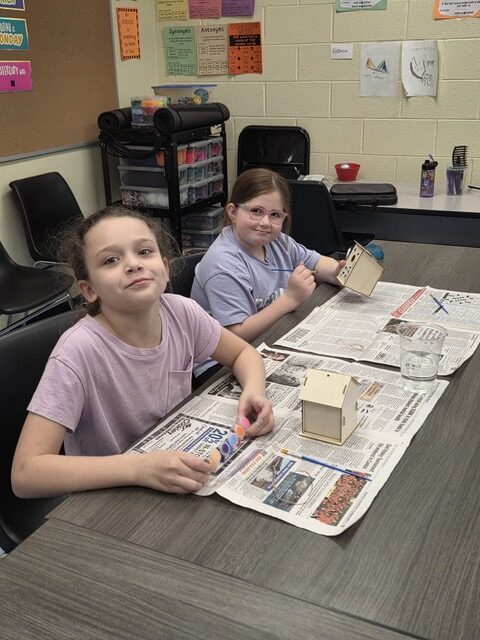 Two girls making birdhouses
