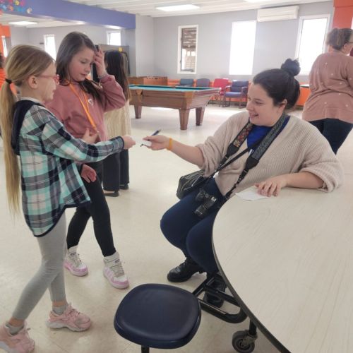 Lady handing children a piece of paper