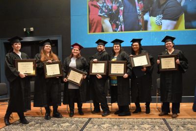 Graduates pose with framed certificates