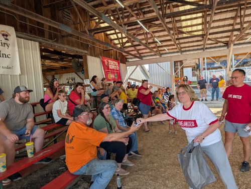 United Way staff hand out cow promo items to the crowd gathering to watch Cow Kissing for ALICE