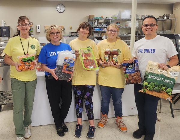 United Way staff pose with BOCES instructor and students holding food supply items.
